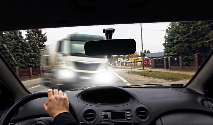 First-person view from a driver's seat: a white truck approaches with bright headlights and motion blur.